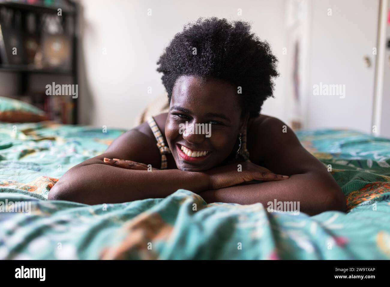 Donna sorridente sdraiata sul letto in camera da letto Foto Stock