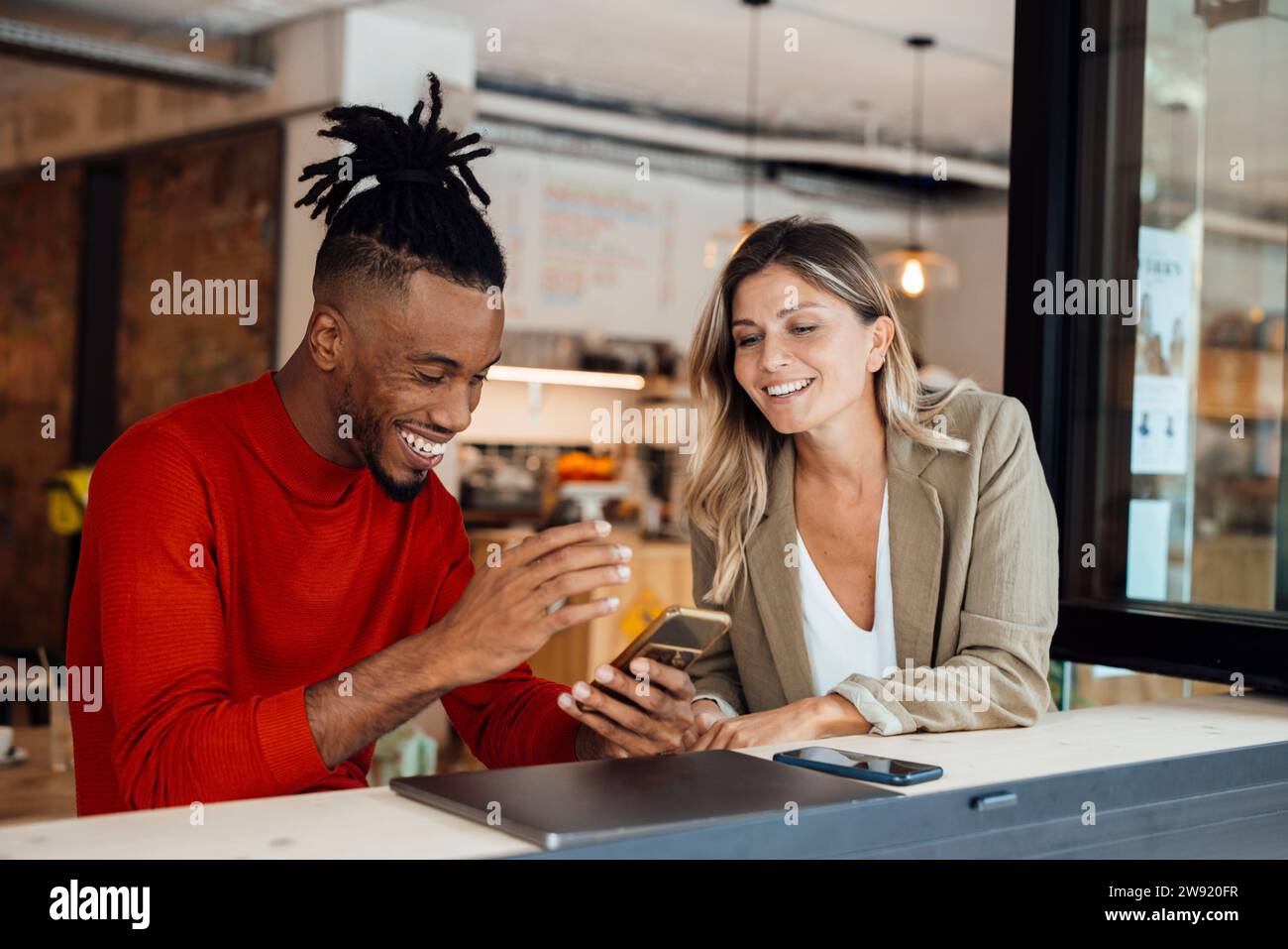 Collega felice che usa lo smartphone da una donna d'affari al bar Foto Stock