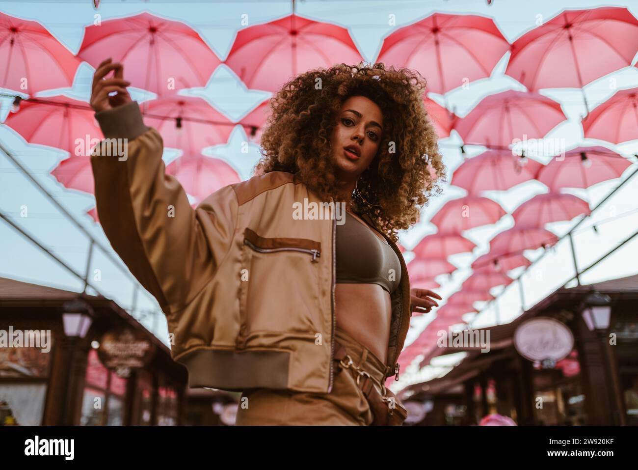 Bella donna che balla sotto gli ombrelli rosa Foto Stock
