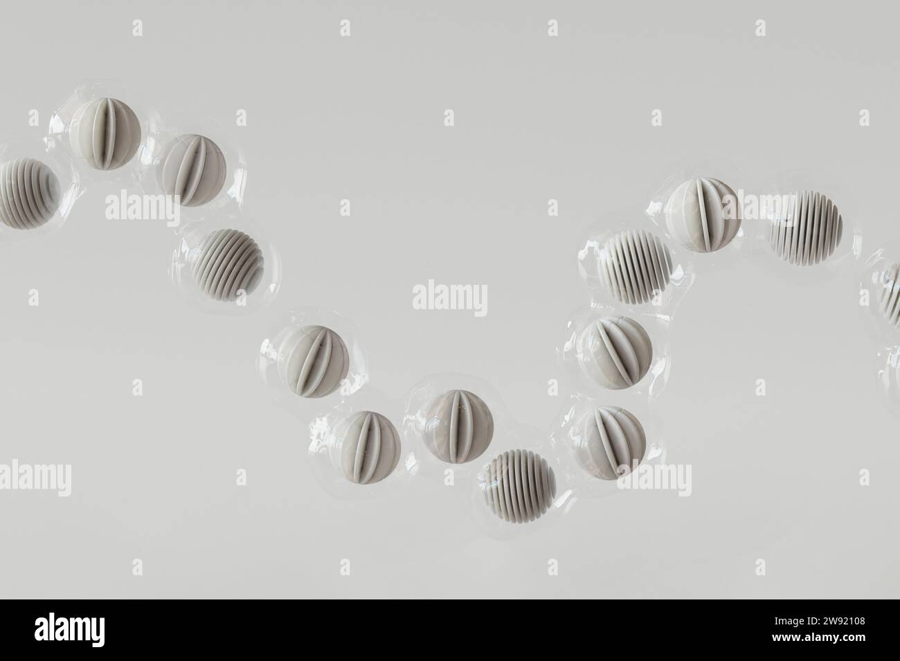 Rappresentazione 3D di una fila di sfere rivestite in plastica che galleggiano su sfondo bianco Foto Stock