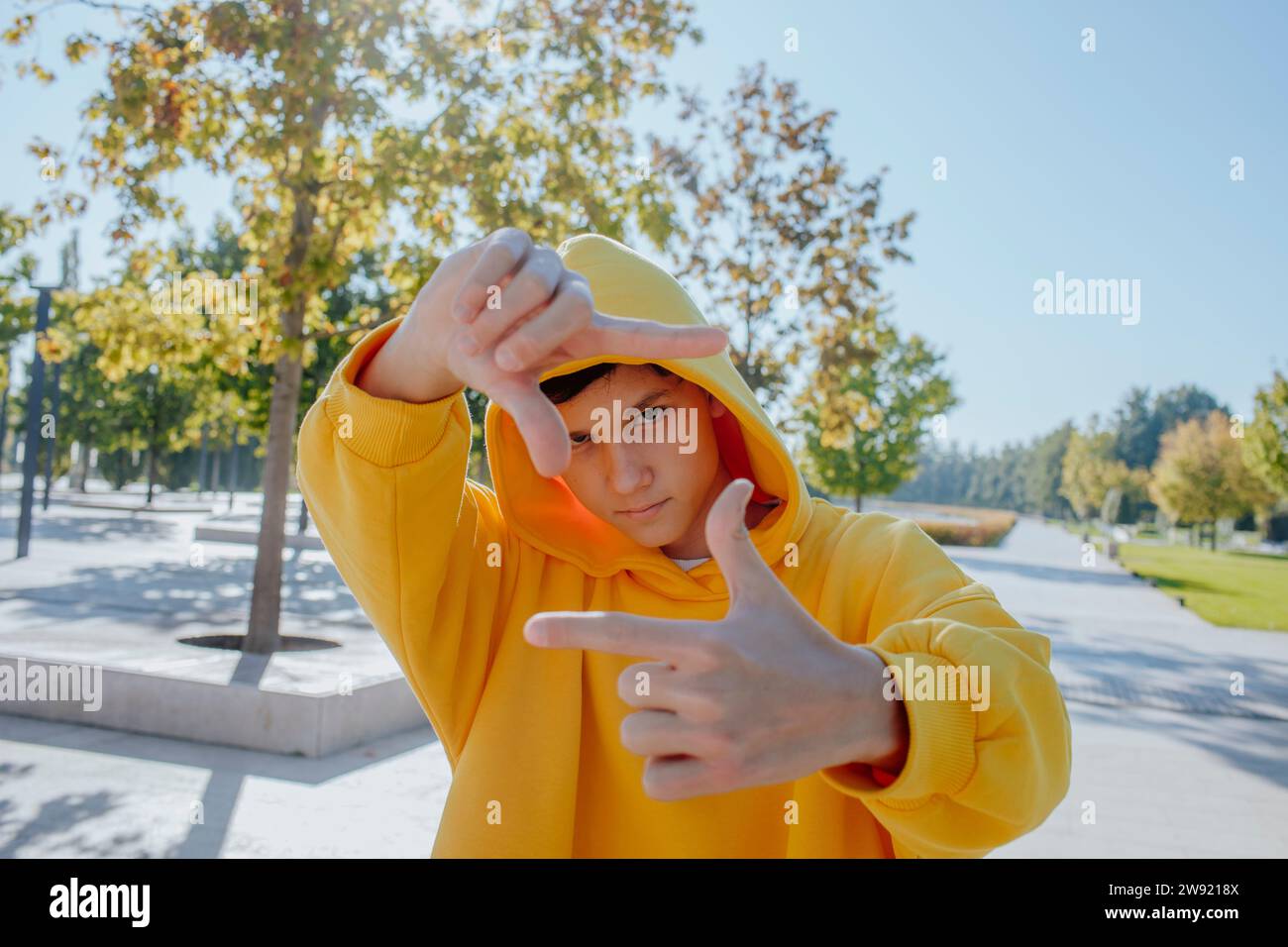 Ragazzo adolescente che guarda attraverso la cornice delle dita nelle giornate di sole Foto Stock