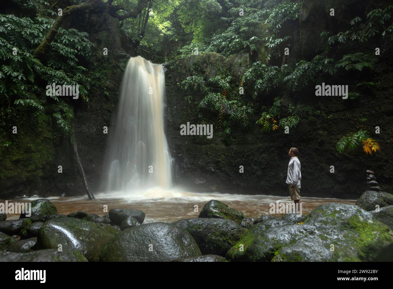 Giovane uomo che guarda la cascata nella foresta pluviale Foto Stock