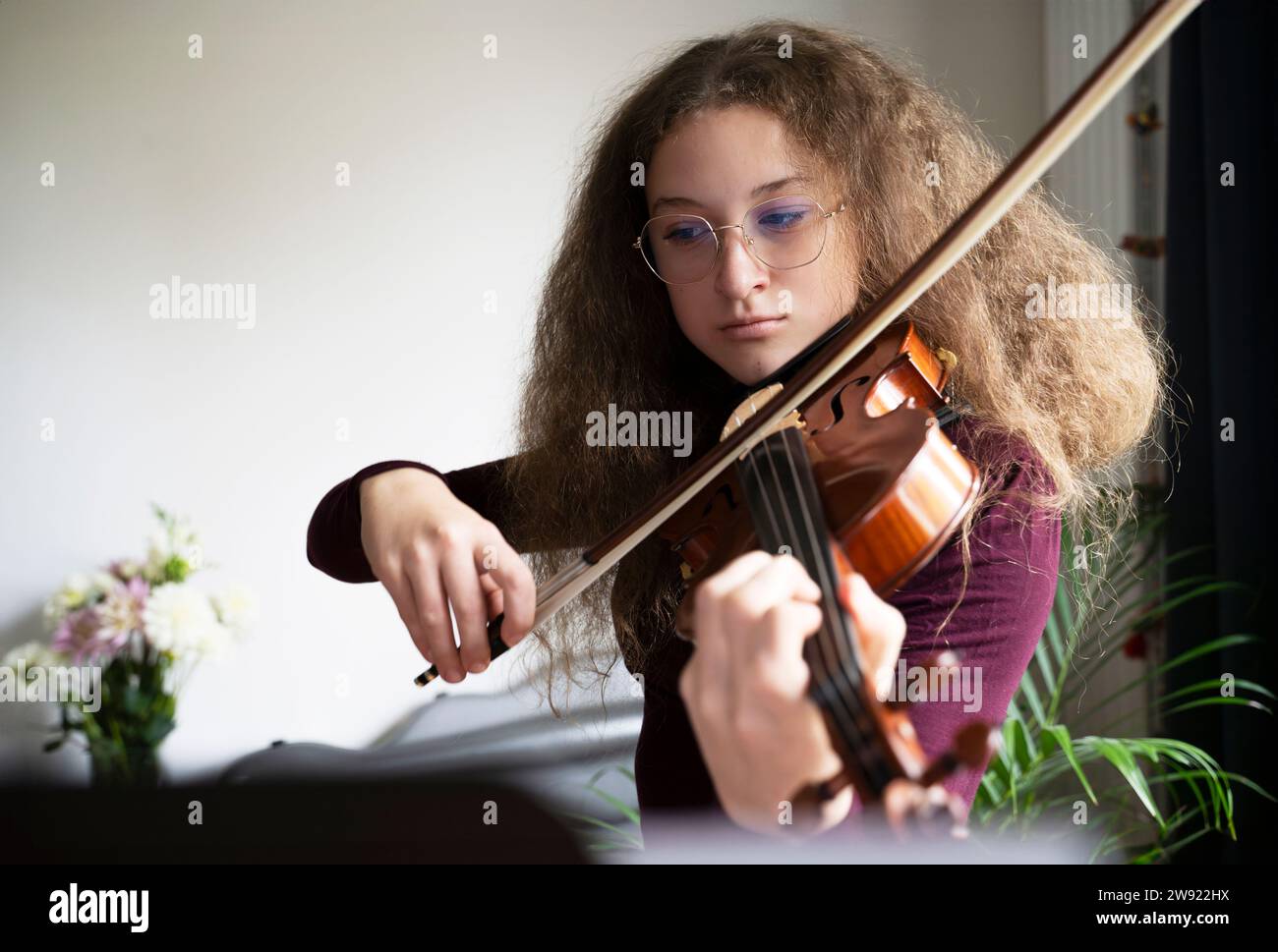 Ragazza dai capelli frizzanti che gioca il violino a casa Foto Stock