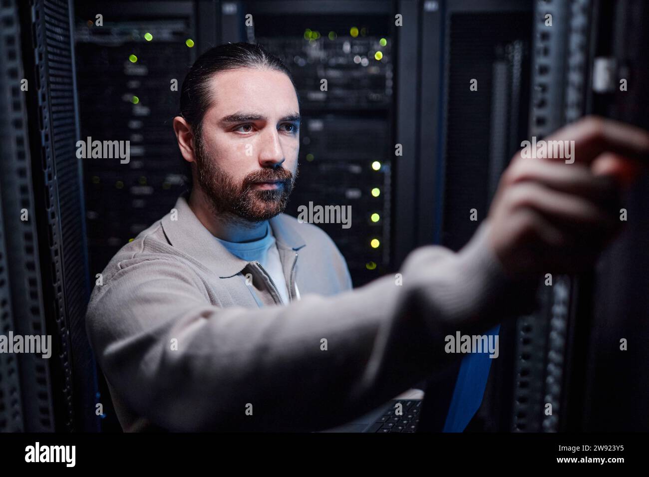 Giovane ingegnere che lavora nella sala server Foto Stock