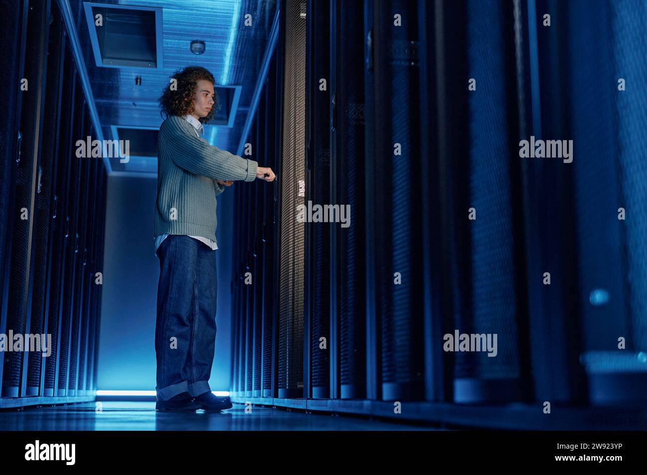 Giovane ingegnere che apre le porte alle apparecchiature server del data center Foto Stock