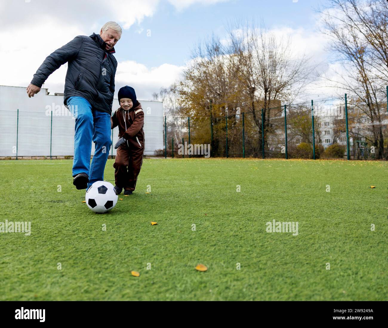 Nipote e nonno si divertono a giocare con la palla al campo da calcio Foto Stock