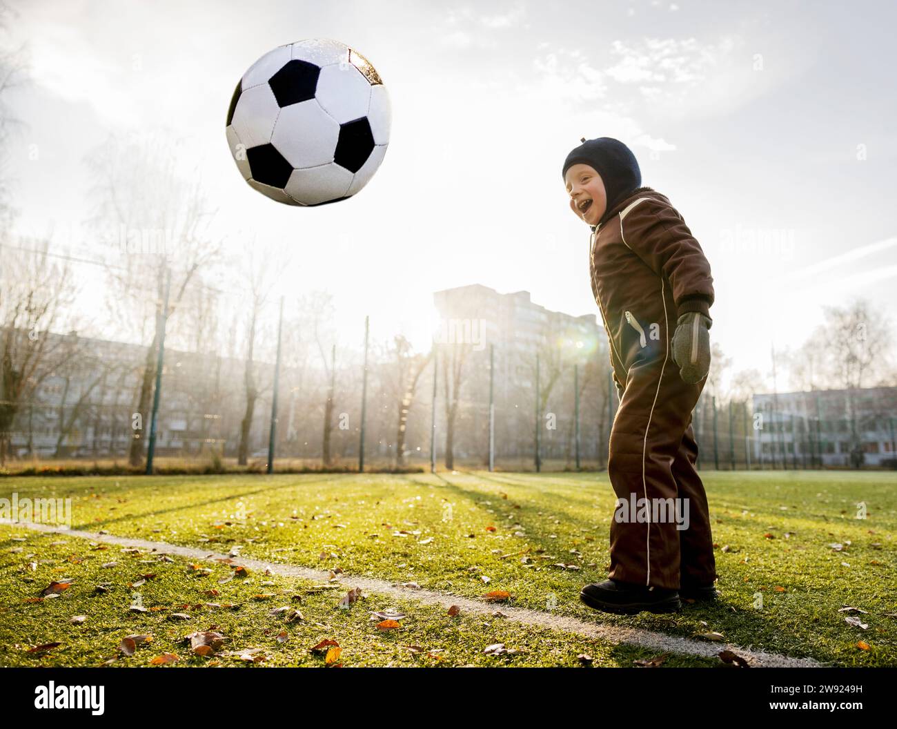Felice ragazzo che gioca con la palla al campo da calcio Foto Stock