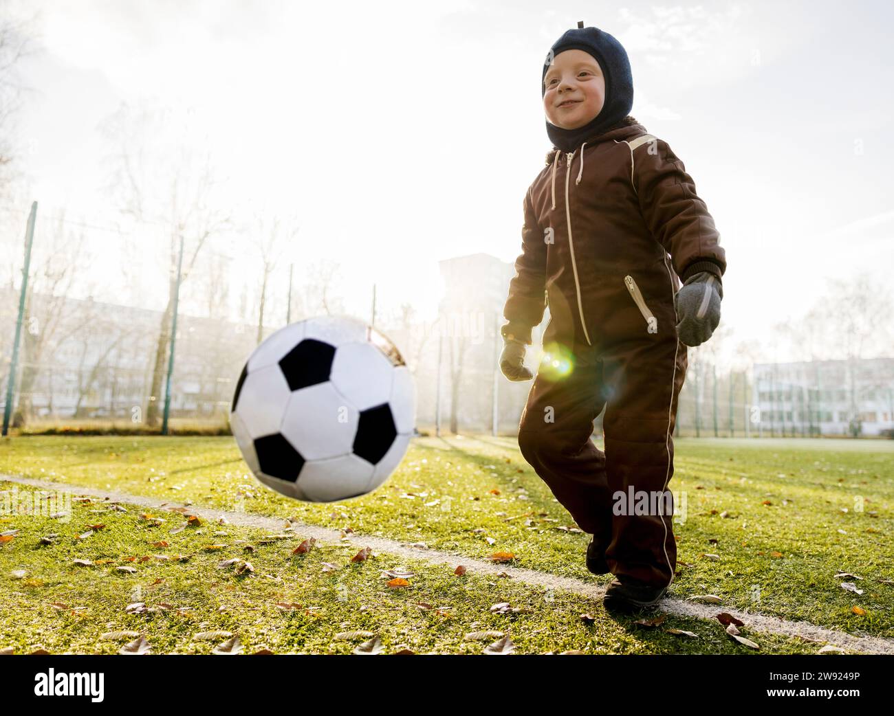 Ragazzo sorridente che gioca con la palla al campo da calcio Foto Stock