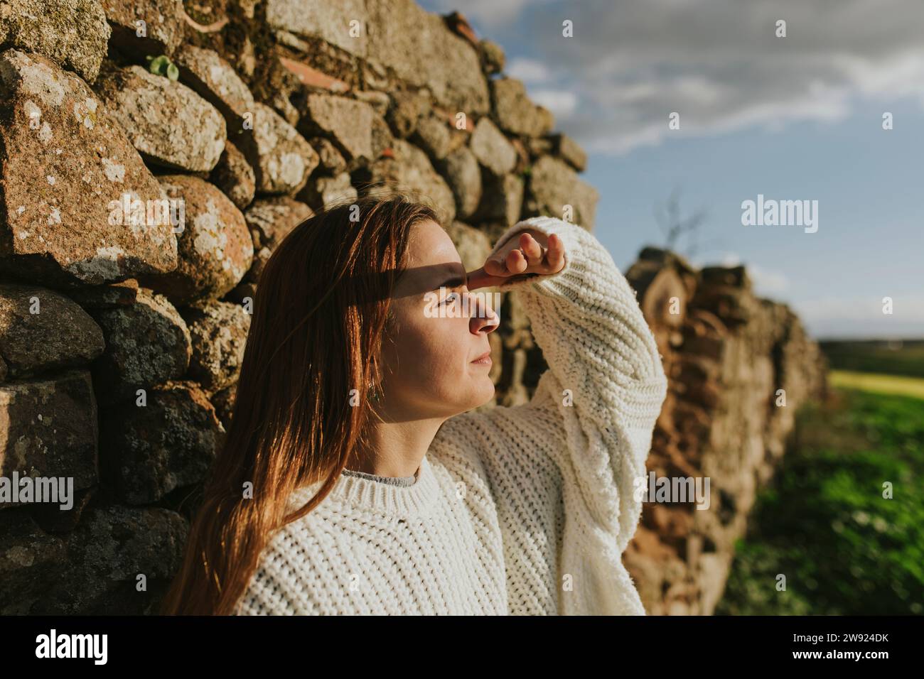 Giovane donna che scherma gli occhi con le mani nelle giornate di sole Foto Stock