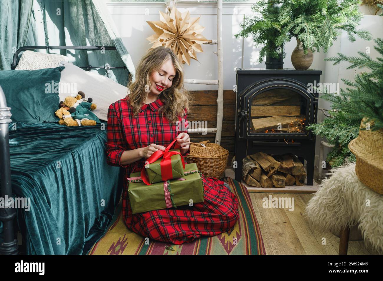 Felice donna che apre i regali di Natale a casa Foto Stock