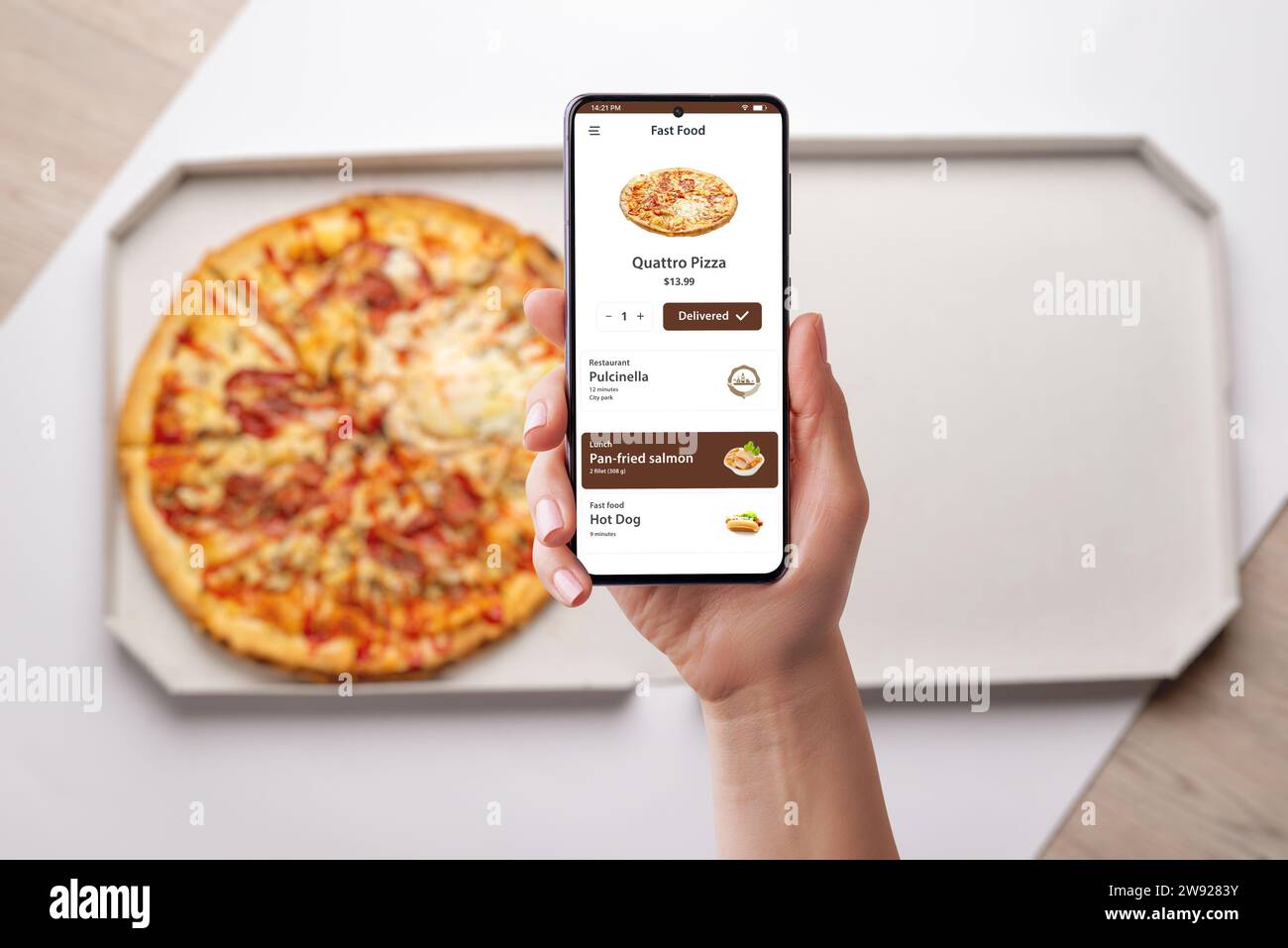 Donna ordina e apprezza una pizza Quatro, consegnata alla sua scrivania tramite una moderna app per smartphone. Design senza cuciture per una deliziosa esperienza culinaria Foto Stock