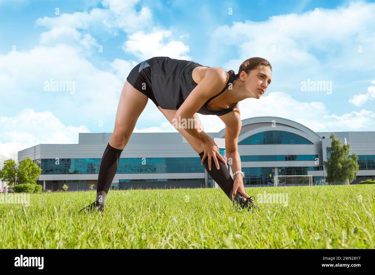 Il bellissimo giovane corridore si riscalda sul campo di calcio prima della gara. Concetto sportivo. Supporti misti Foto Stock