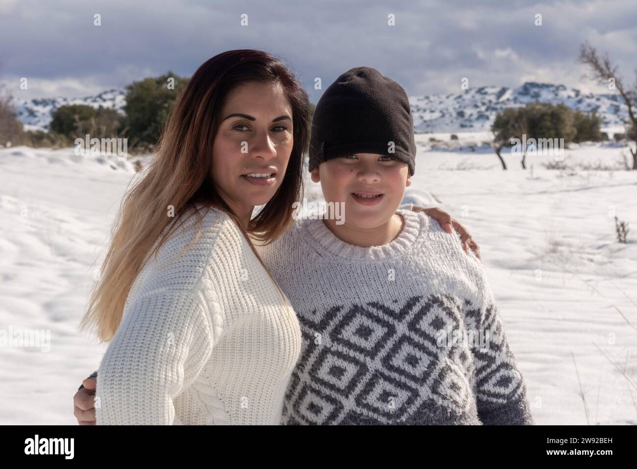 Ritratto di madre e bambino che guardano la macchina fotografica in un campo innevato Foto Stock