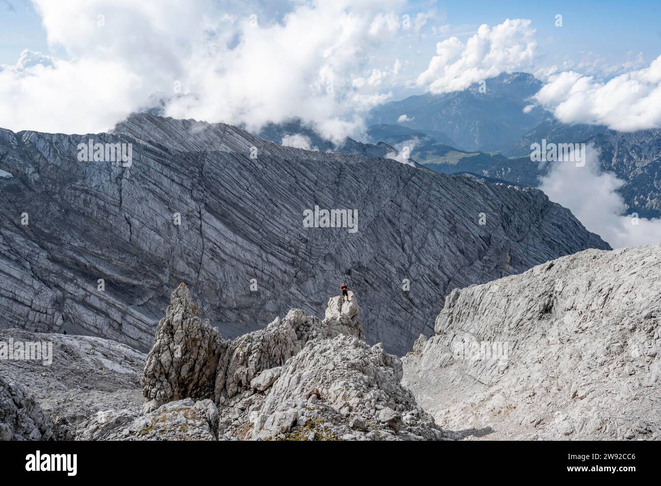 Alpinista sulla cima rocciosa, discesa a Ofentalscharte, dietro la parete rocciosa di Ofentalschneid, tour in montagna fino alla cima dell'Hochkalter, Hochkalter Foto Stock