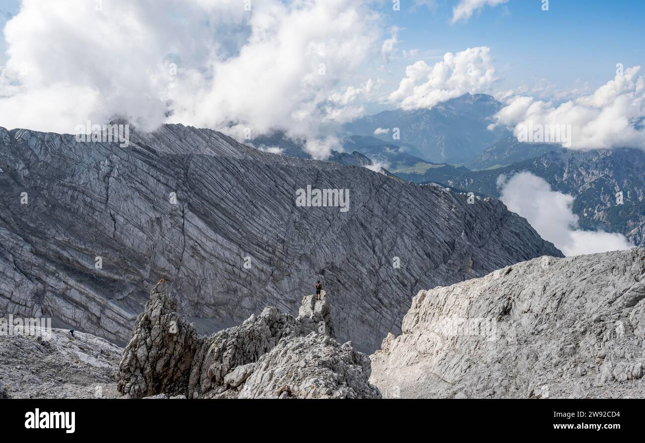 Alpinista sulla cima rocciosa, discesa a Ofentalscharte, dietro la parete rocciosa di Ofentalschneid, tour in montagna fino alla cima dell'Hochkalter, Hochkalter Foto Stock