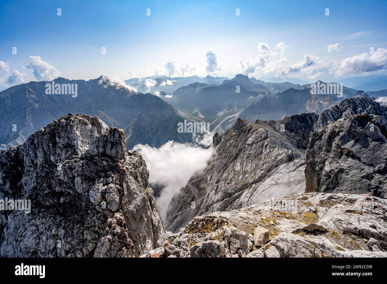 Vista dalla cima dell'Hochkalter, ripido paesaggio roccioso di montagna, dietro la cima del crinale di Watzmann e delle Alpi di Steinernes Meer, Berchtesgaden Foto Stock