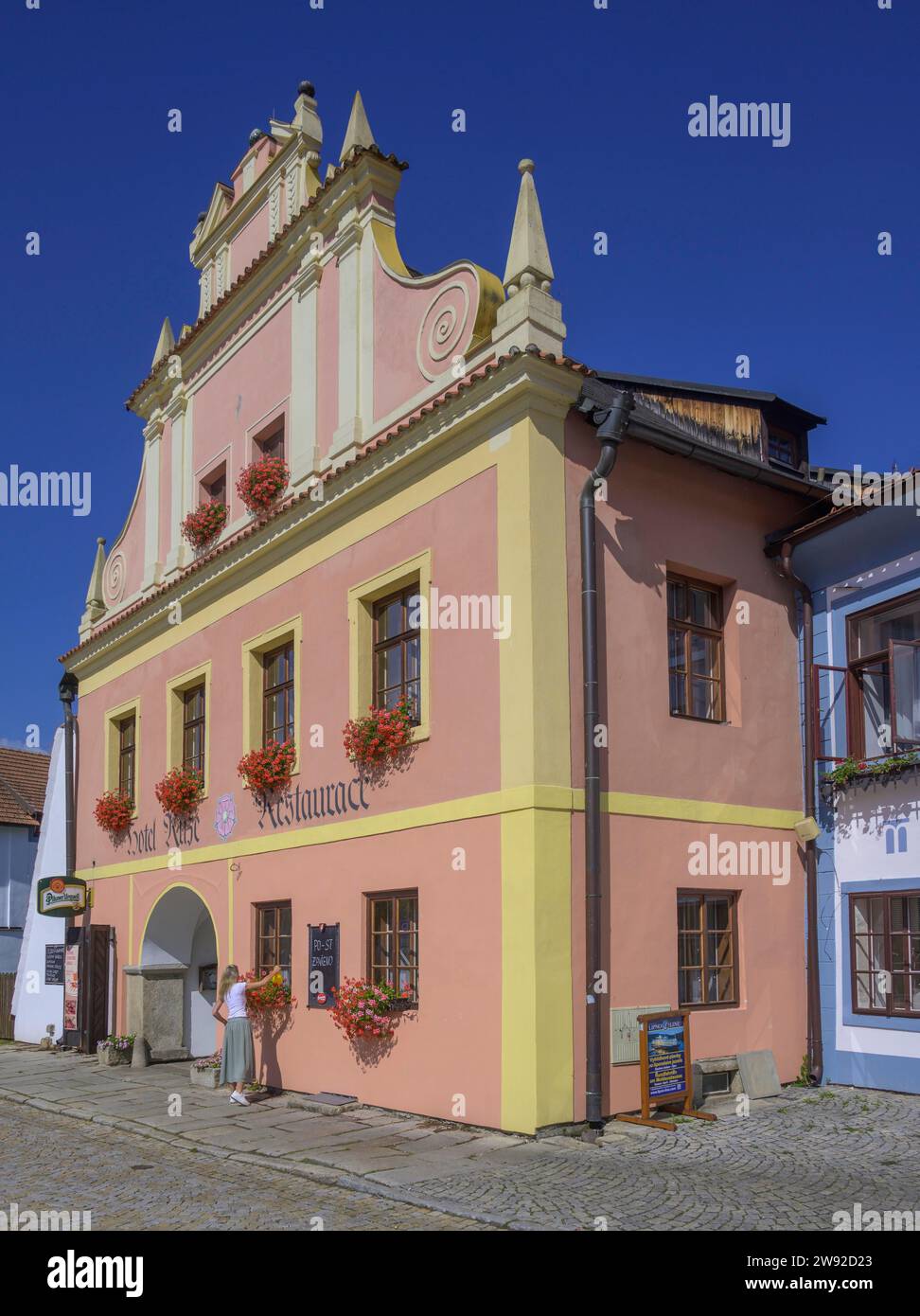 Donna che annaffiava fiori in un edificio storico dell'hotel, Rozmberk nad Vltavou, Boemia meridionale, Repubblica Ceca Foto Stock