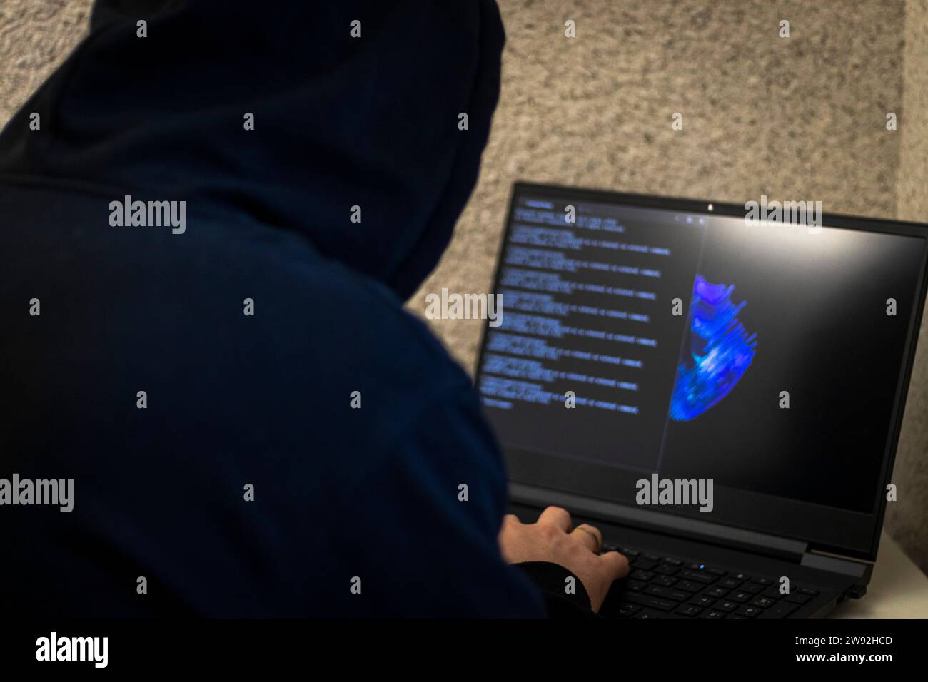 Un uomo sembrava un hacker in un cofano seduto davanti al portatile, scrivendo un codice Foto Stock Un uomo sembrava un hacker in un cofano seduto davanti al portatile, scrivendo un codice Foto Stock