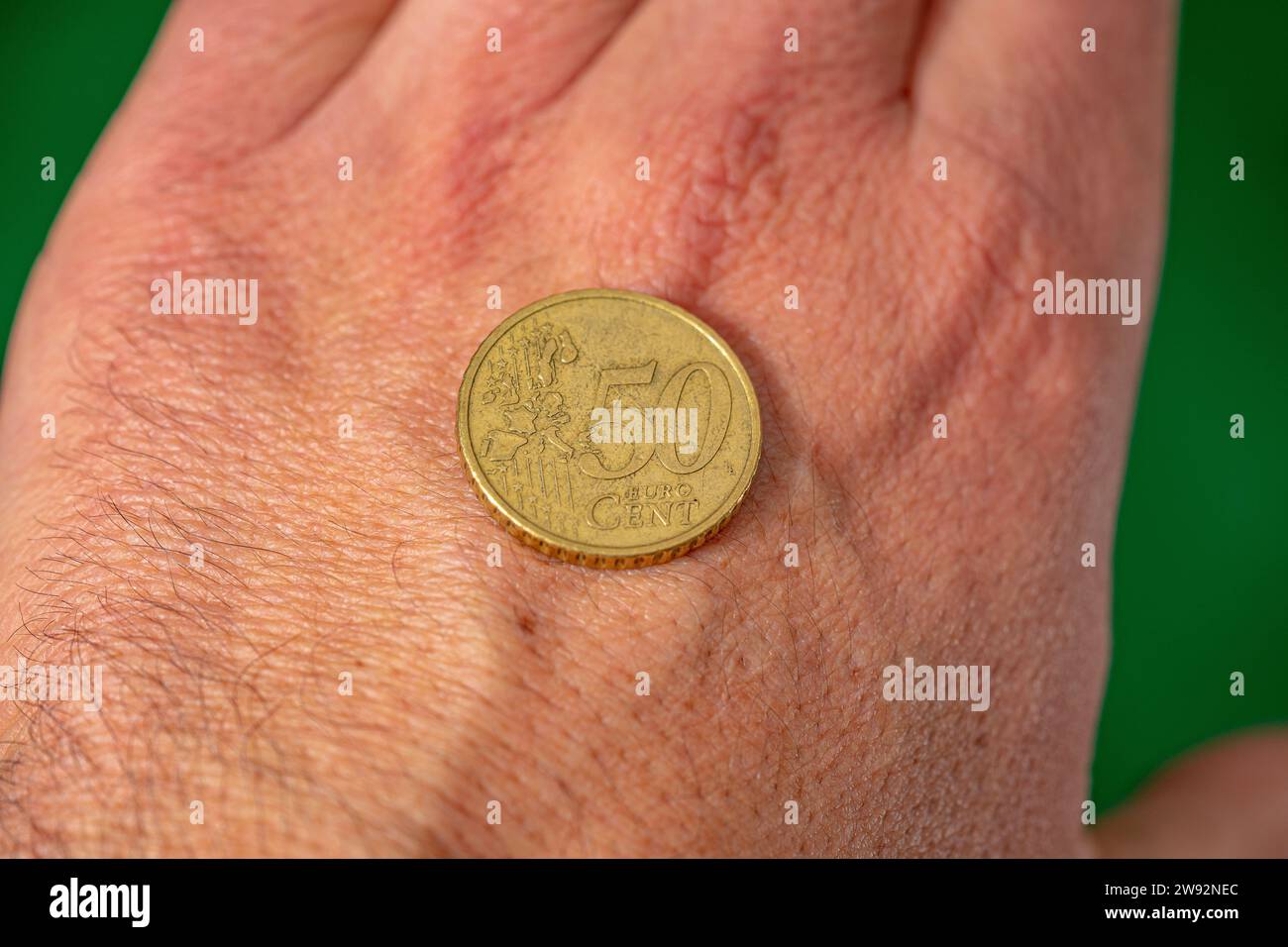 faccia in moneta da 50 centesimi di euro sul dorso della mano. sfondo verde Foto Stock