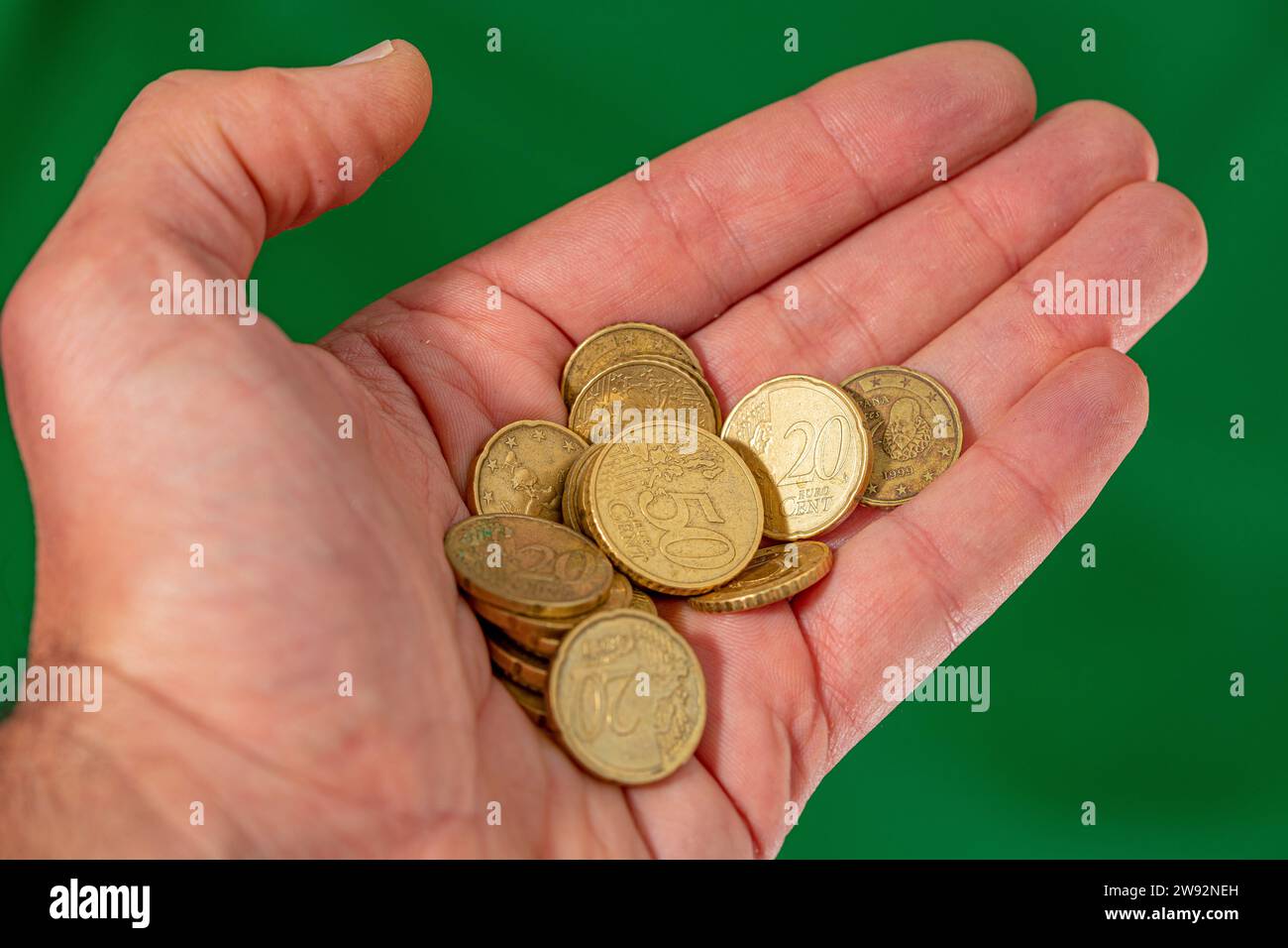 Pile di monete d'oro in mano isolate su sfondo verde. Primo piano. Foto Stock