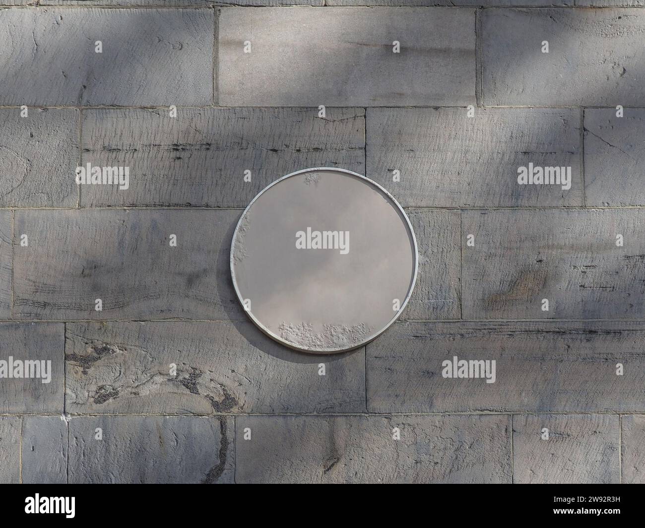 placca rotonda vuota su un muro di pietra Foto Stock
