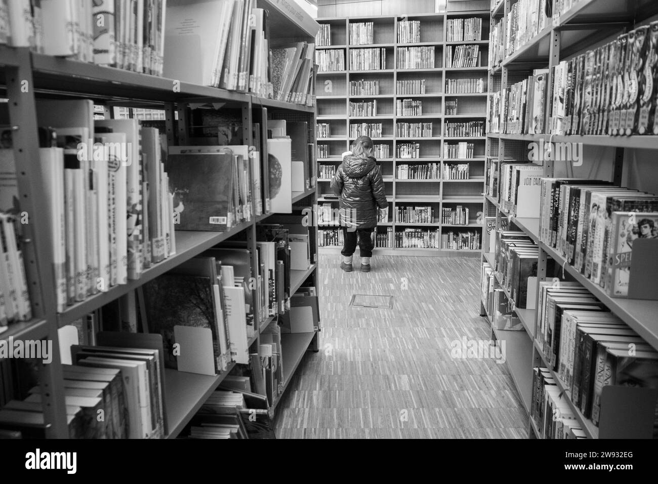 Un bambino di 4 anni che sceglie un libro in una biblioteca. Foto Stock