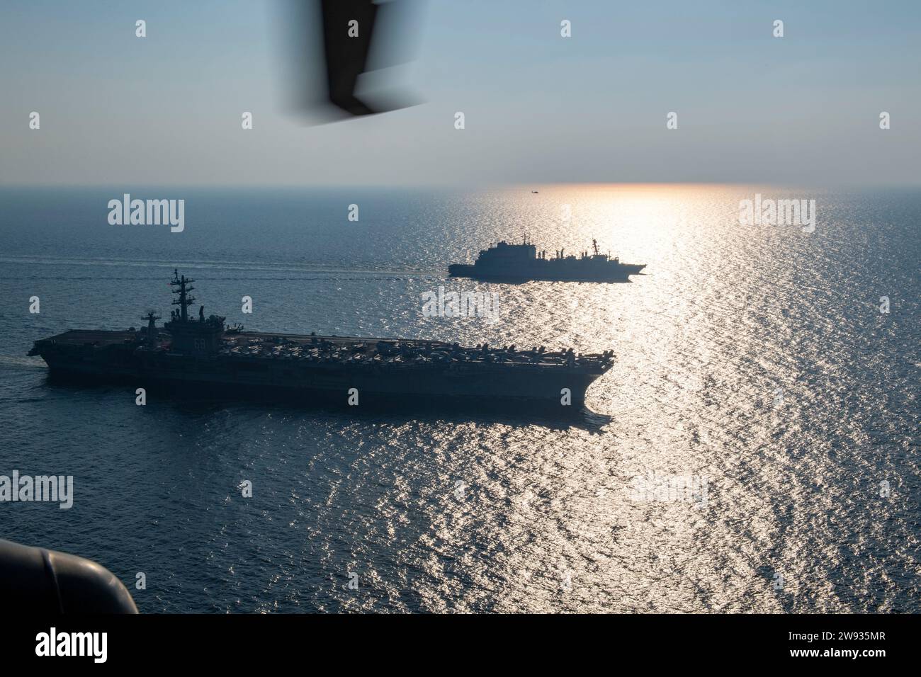 La portaerei USS Dwight D. Eisenhower (CVN 69), la nave da carico secco USNS Alan Shepard (T-AKE 3) e il cacciatorpediniere missilistico guidato USS Gravely (DDG 107) e un elicottero MH-60S Sea Hawk, attaccato al "Dusty Dogs" dell'Helicopter Sea Combat Squadron (HSC) 7, condurre un rifornimento in mare nel Golfo Arabico, 8 dicembre 2023. Il Dwight D. Eisenhower Carrier Strike Group è schierato nell'area operativa della 5th Fleet degli Stati Uniti per sostenere la sicurezza marittima e la stabilità nella regione del Medio Oriente. (Foto della Marina degli Stati Uniti di Mass Communication Specialist 2nd Class Merissa Daley) Foto Stock