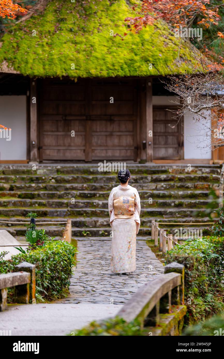 Kyoto, Giappone. Donna che indossa kimono nel giardino autunnale del tempio di Honen-in. Gli alberi d'acero diventano rossi in autunno. Edificio tradizionale Giapponese con scale in pietra Foto Stock