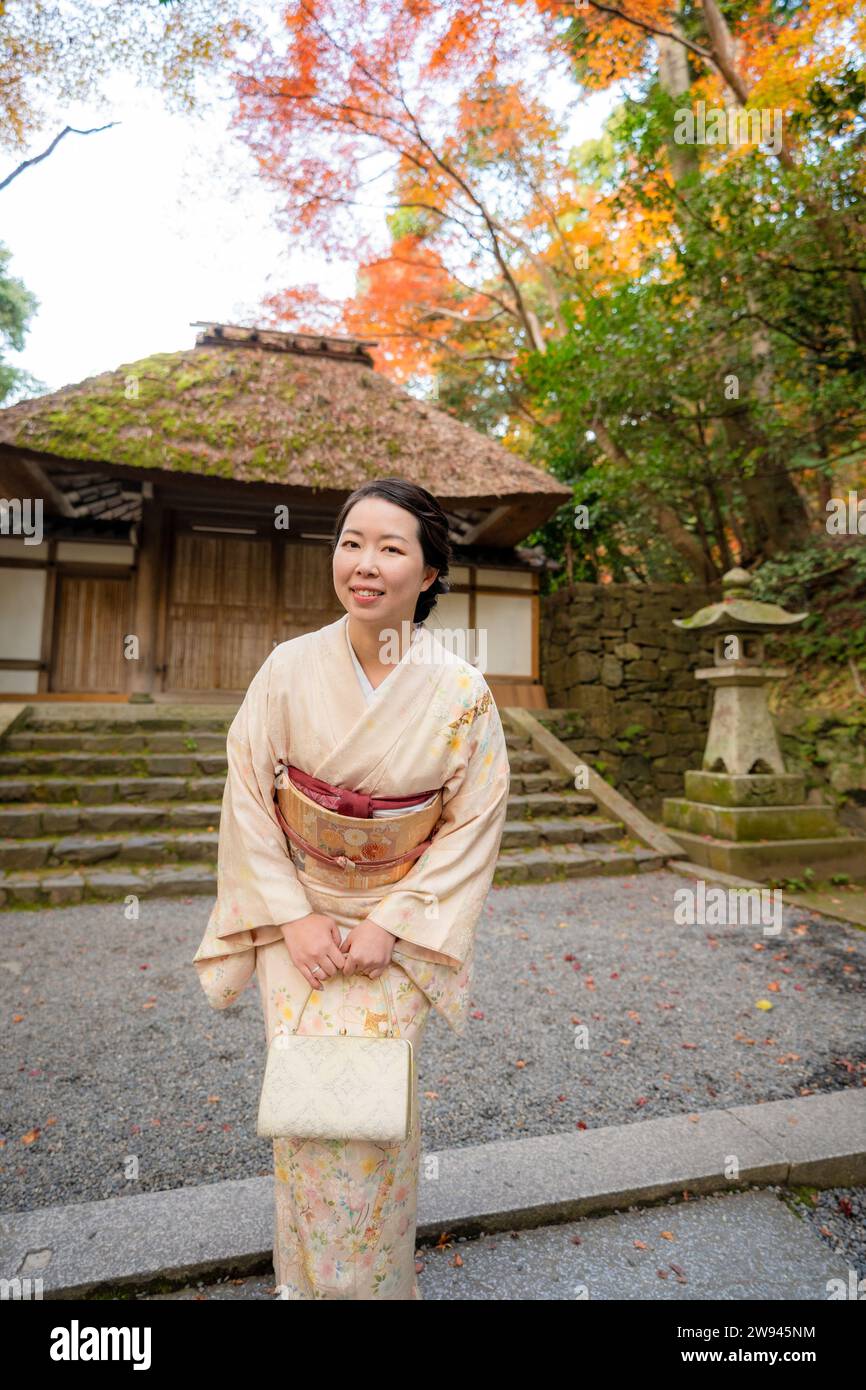 Kyoto, Giappone. Donna che indossa kimono nel giardino autunnale del tempio di Honen-in. Gli alberi d'acero diventano rossi in autunno. Edificio tradizionale Giapponese con scale in pietra Foto Stock