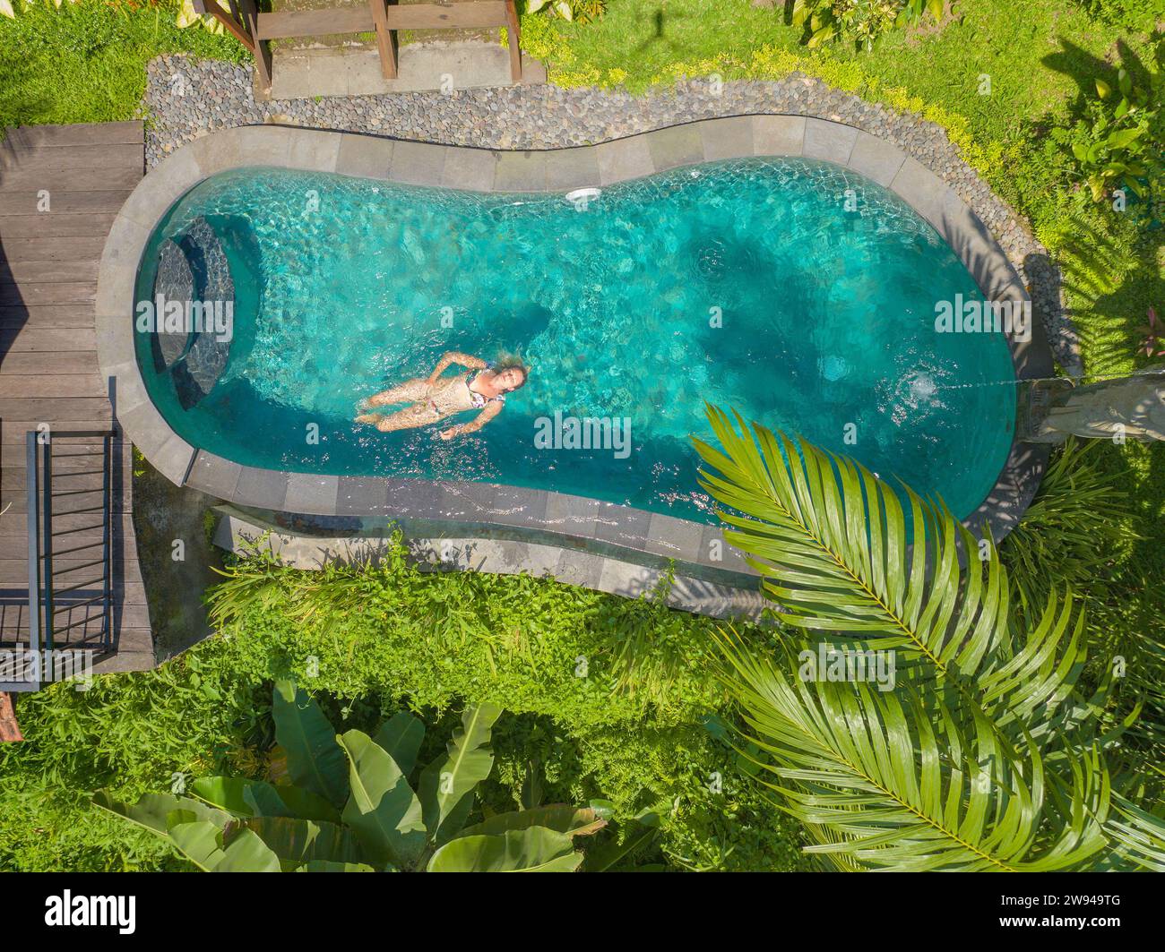 Vista aerea di una giovane donna che si rilassa in una piscina, nella zona rurale di Bali Foto Stock
