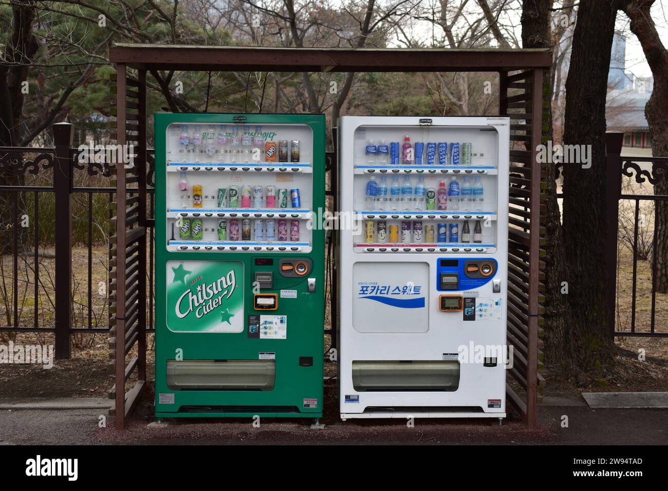 Un distributore automatico di bevande verde e bianco sotto un tetto di legno nel parco intorno al palazzo Gyeonbokgung Foto Stock