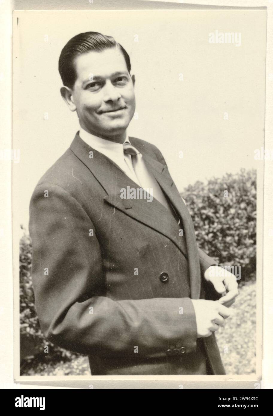Uomo sorridente sconosciuto, con una siepe sullo sfondo, Anonymous, 1951 fotografare uomo sorridente sconosciuto, con una siepe sullo sfondo. supporto fotografico stampa in argento gelatina Foto Stock