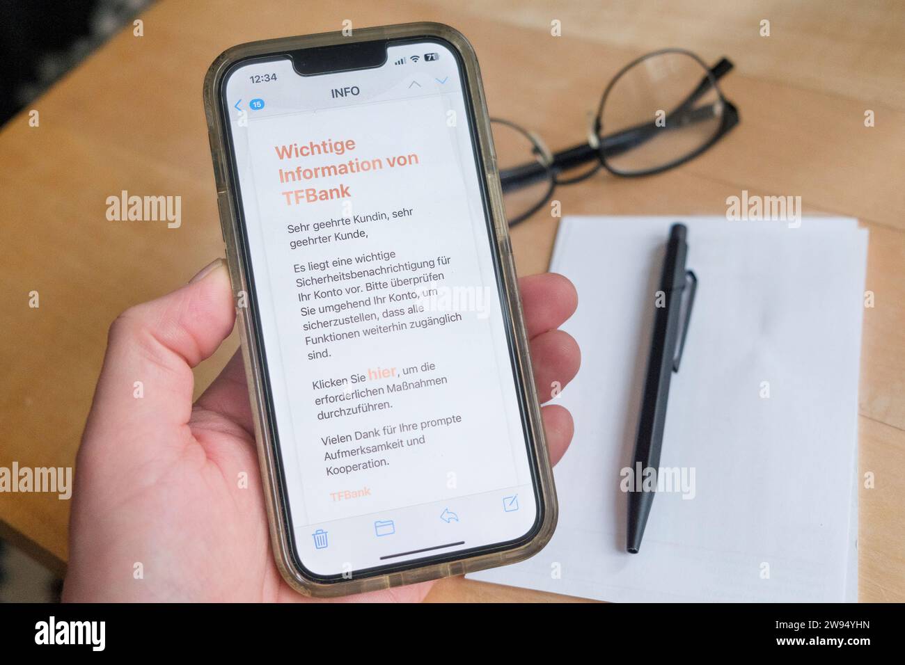 Mano che tiene in mano un telefono cellulare che mostra un tentativo di phishing tramite e-mail, qui una falsa e-mail della TF Bank svedese Foto Stock