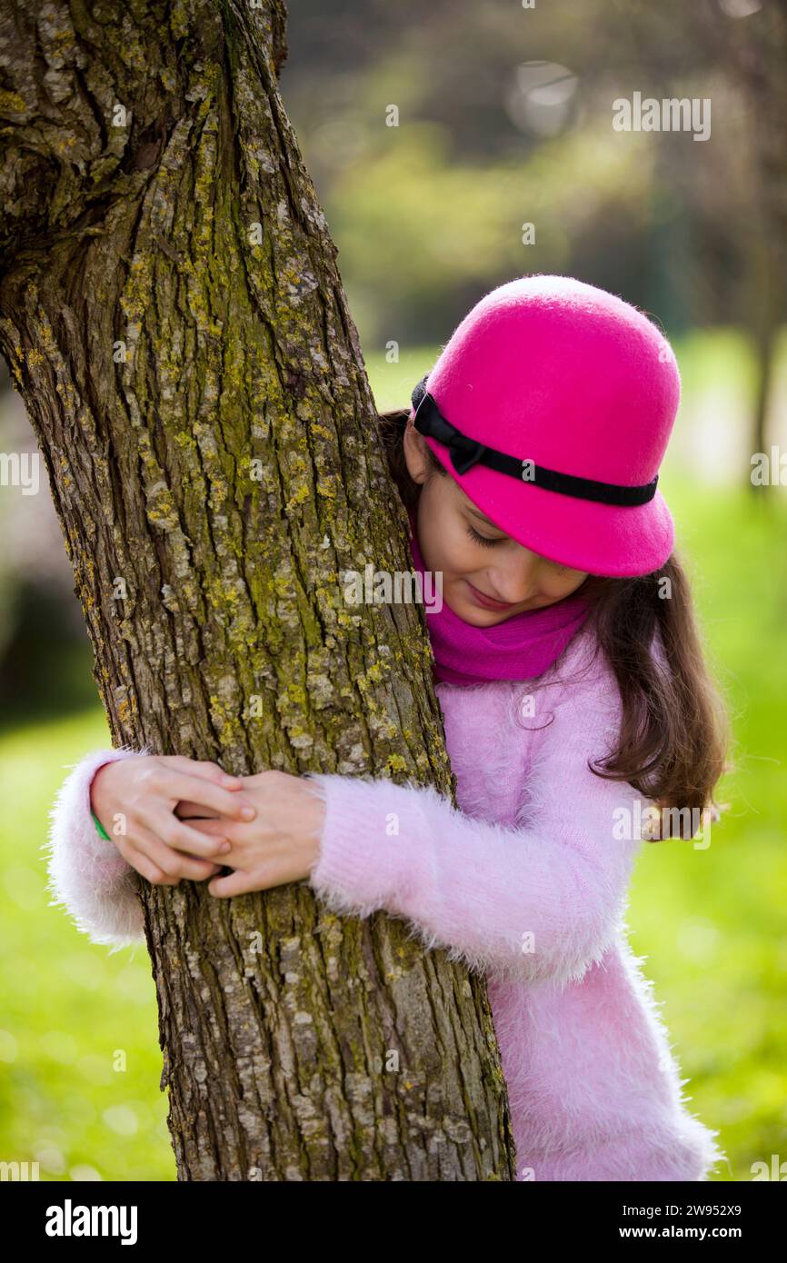 Bambina femmina che abbracciano un albero Foto Stock