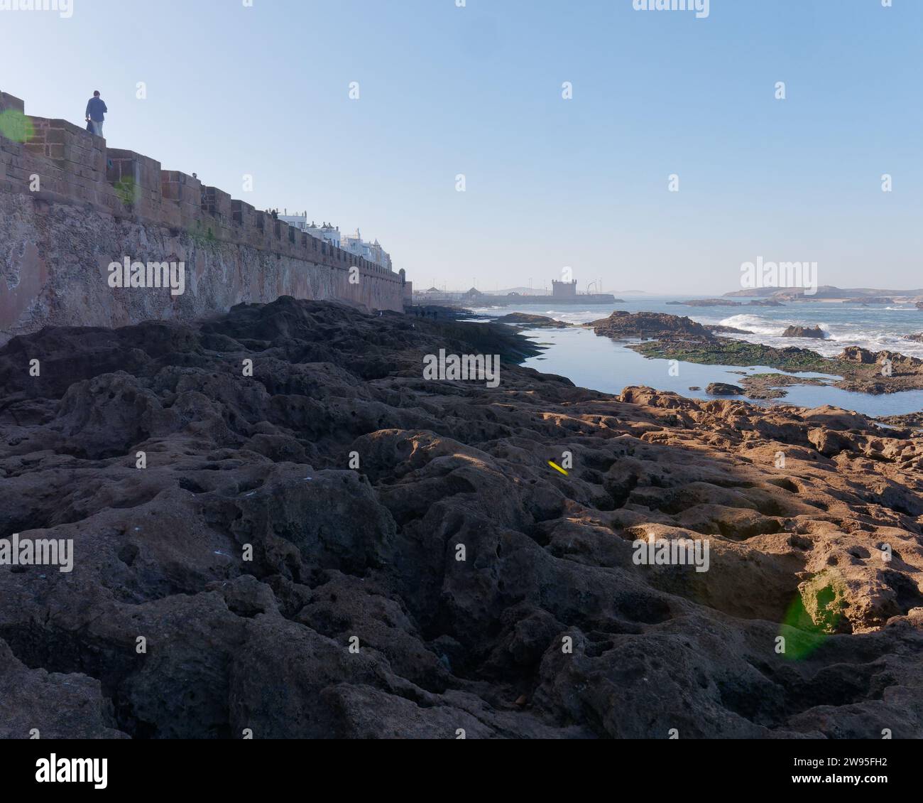 Costa rocciosa con qualcuno che cammina sulle mura della città di Medina a Essaouira, Marocco. 23 dicembre 2023 Foto Stock