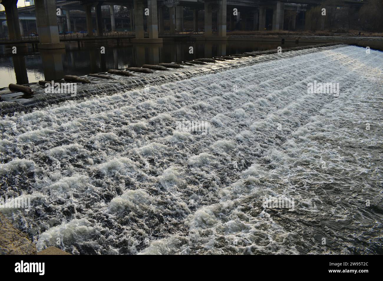 Acqua di un canale che si unisce al fiume Han, che scorre a valle su una piccola diga Foto Stock