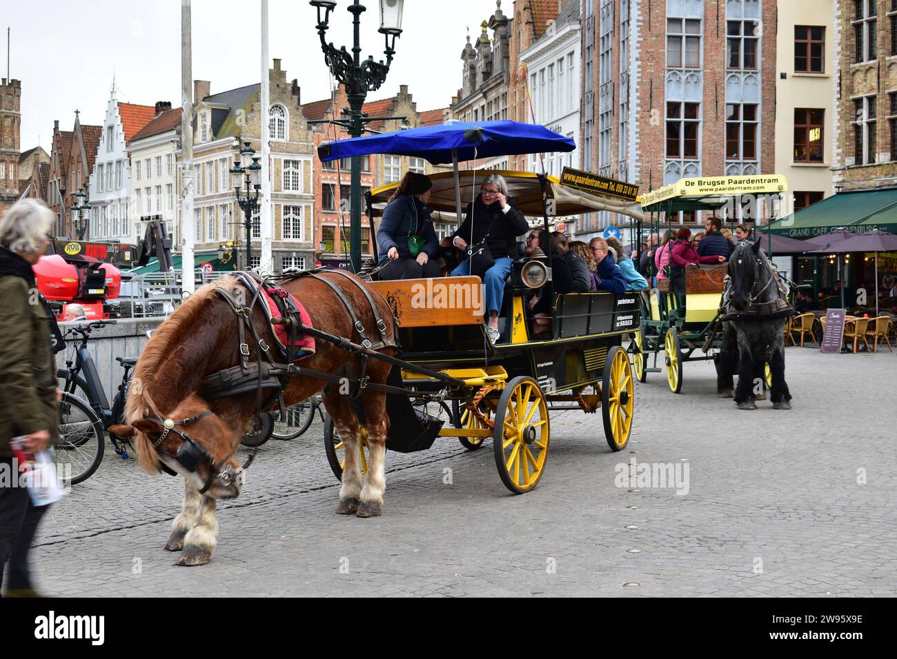 I turisti fanno un tour "il carrozza a cavallo di Bruges" in una carrozza di legno trainata da un cavallo sulla Grand Place nel centro medievale della città di Bruges Foto Stock