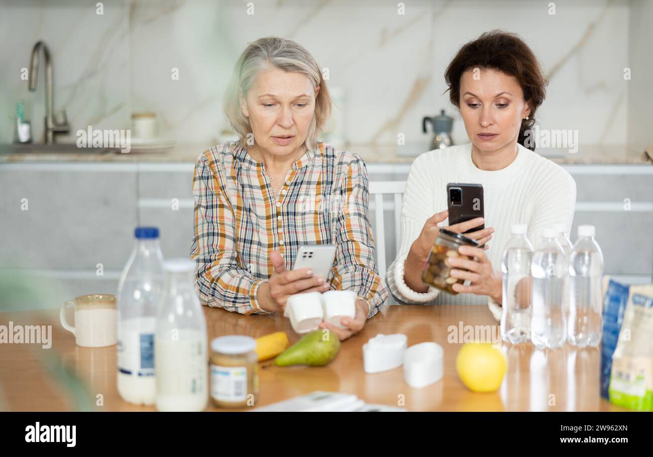 Due donne che scansionano prodotti diversi utilizzando il proprio smartphone Foto Stock