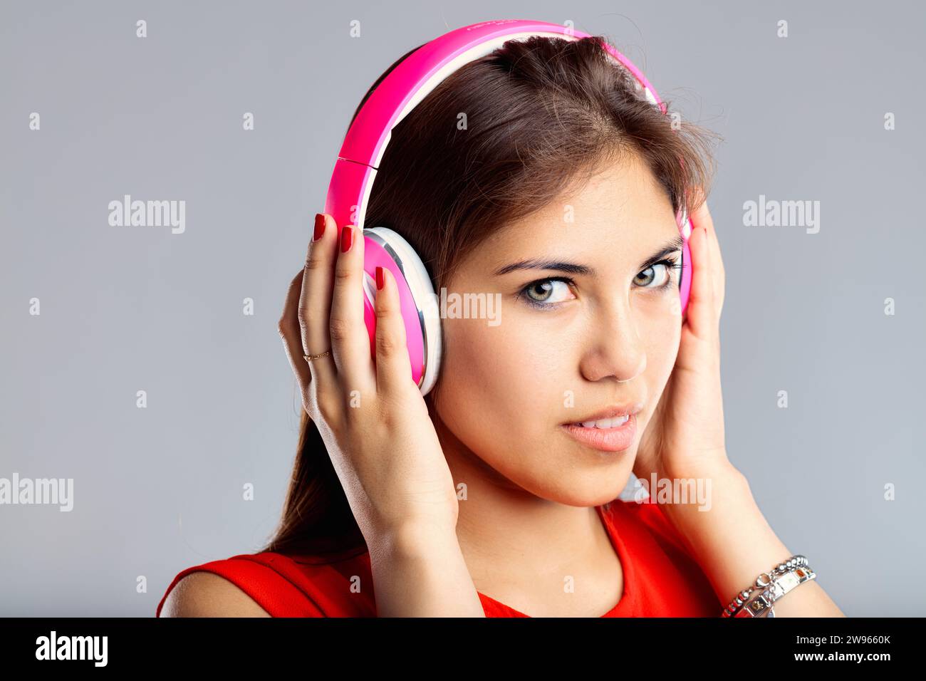 Affascinata dal suono, indossa cuffie rosa, la sua espressione è concentrata e rilassata Foto Stock