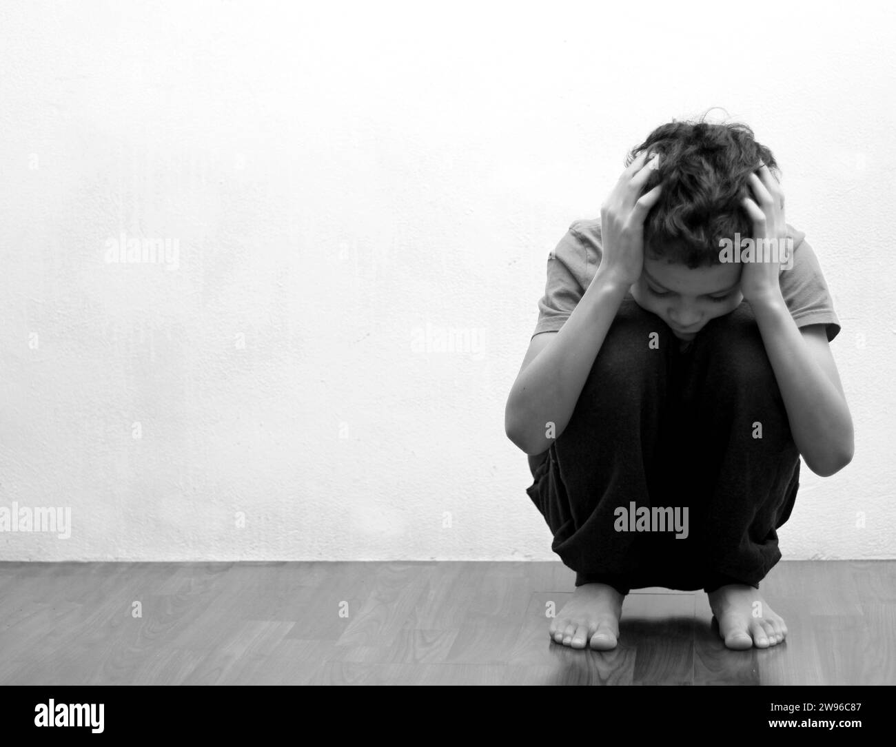 ragazzo che prega in povertà sul pavimento immagine stock senza aiuto piangere da solo e tutto da solo su sfondo bianco foto stock Foto Stock