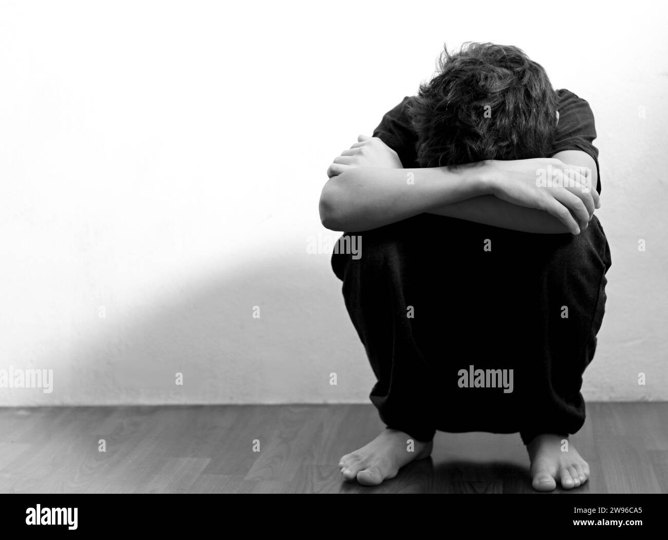 ragazzo che prega in povertà sul pavimento immagine stock senza aiuto piangere da solo e tutto da solo su sfondo bianco foto stock Foto Stock