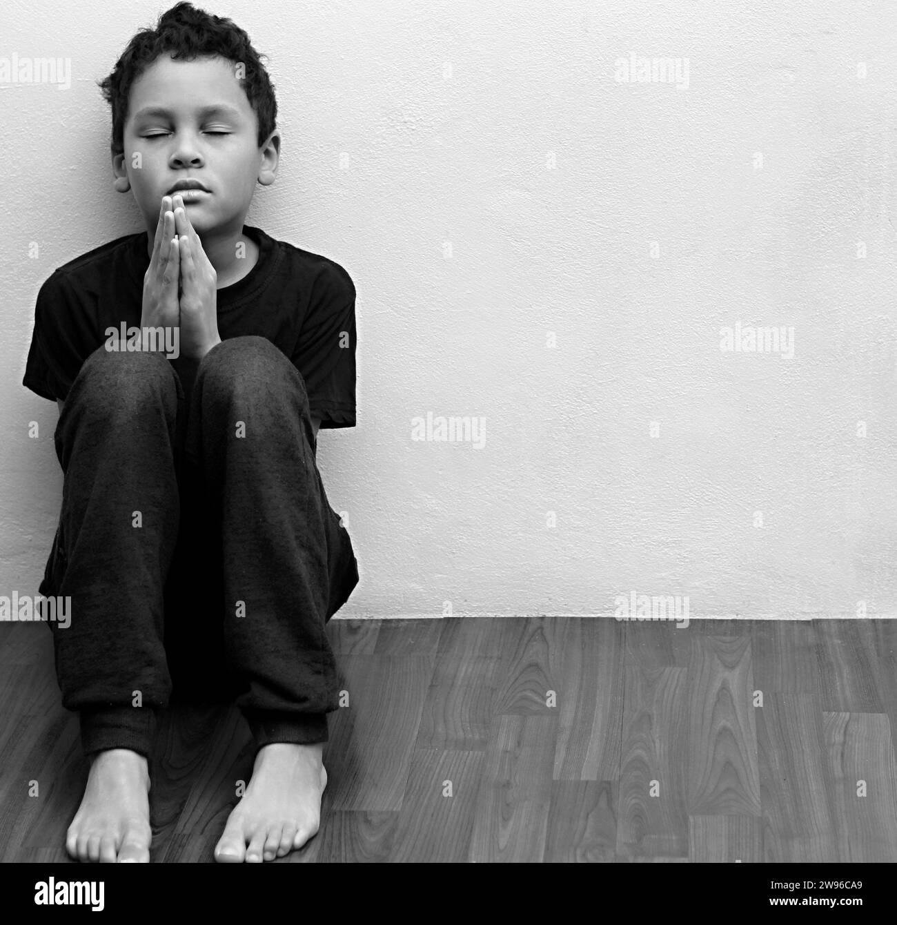 ragazzo che prega in povertà sul pavimento immagine stock senza aiuto piangere da solo e tutto da solo su sfondo bianco foto stock Foto Stock