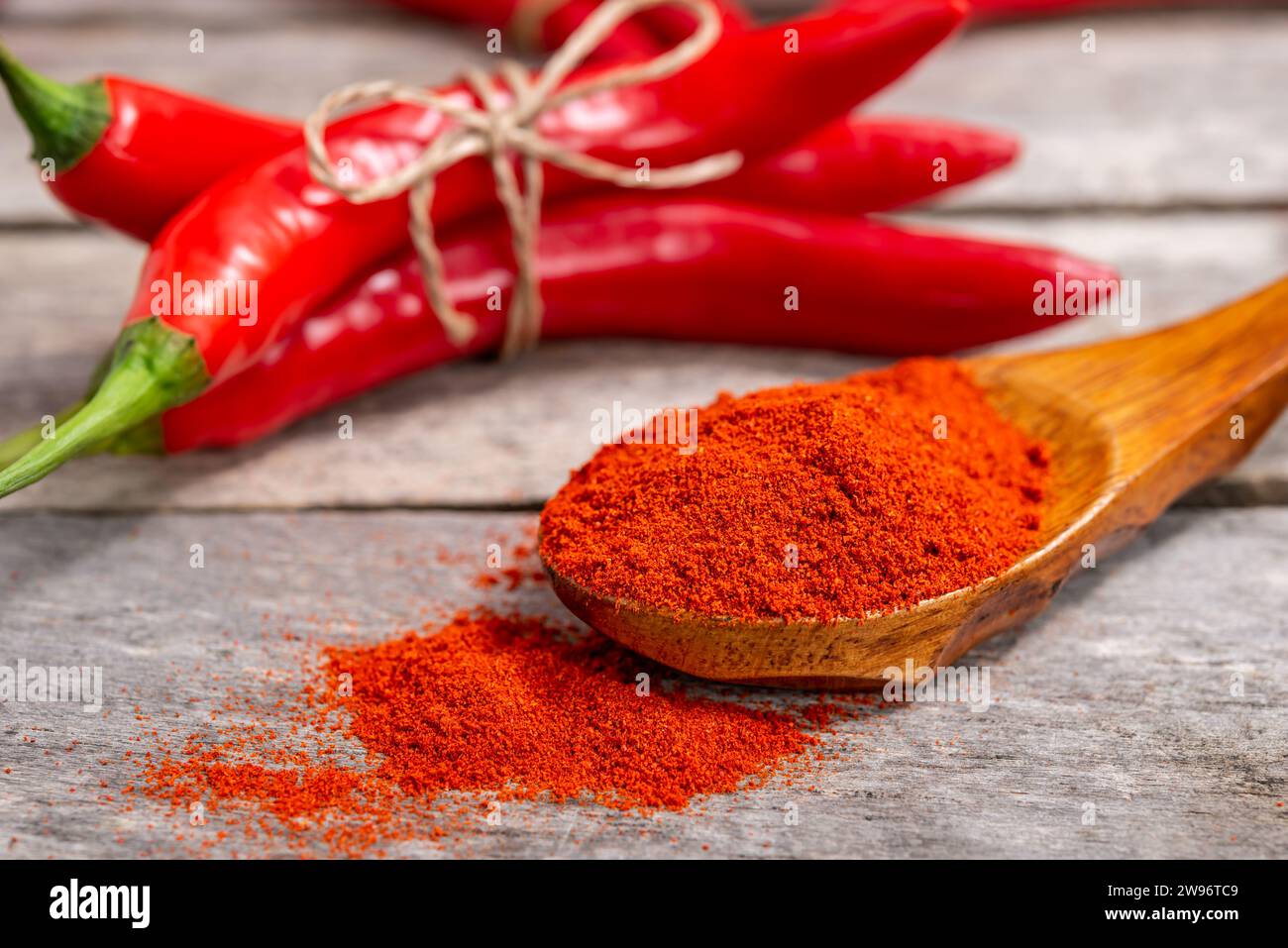 Cucchiaio di legno con pepe macinato e peperoncino rosso fresco sulla vecchia tavola. Messa a fuoco selettiva. Foto Stock