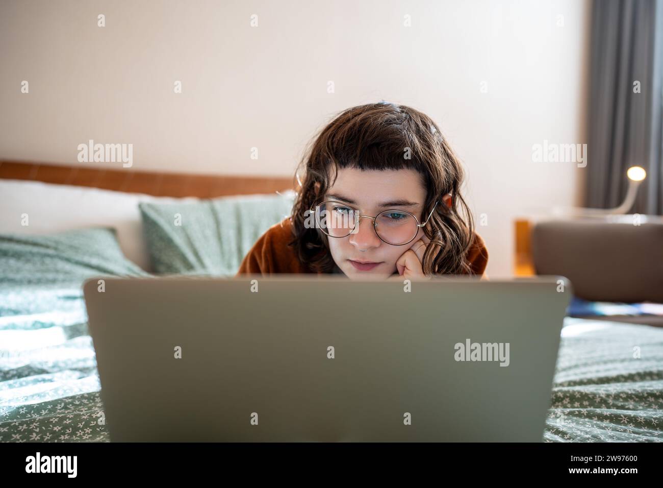 Eccitata ragazza adolescente interessata che guarda film su un computer portatile, passa il fine settimana, passeggia a casa Foto Stock
