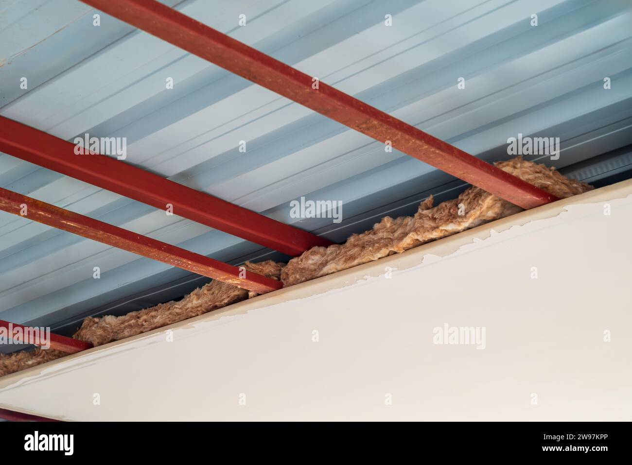 Applicazione di isolamento realizzata con lana di vetro tra l'attico della piccola casa di nuova costruzione Foto Stock