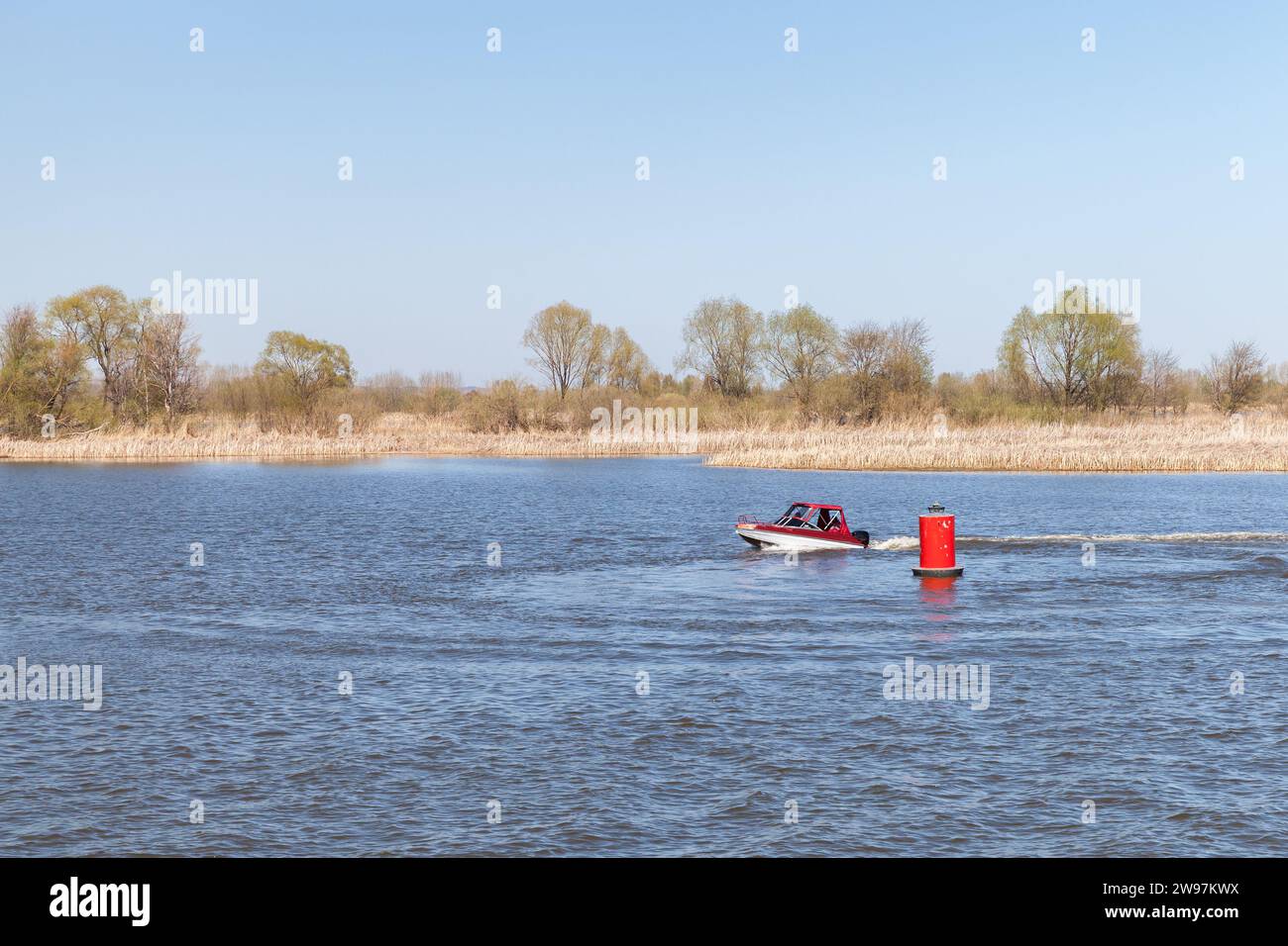La piccola barca a motore naviga lungo il fairway del fiume Volga vicino alla boa rossa. Bolgar, Tatarstan, Russia Foto Stock