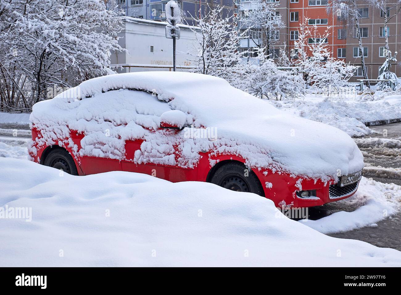 Ryazan, Russia - 24 dicembre 2023: Auto rossa coperta di neve per strada in inverno Foto Stock