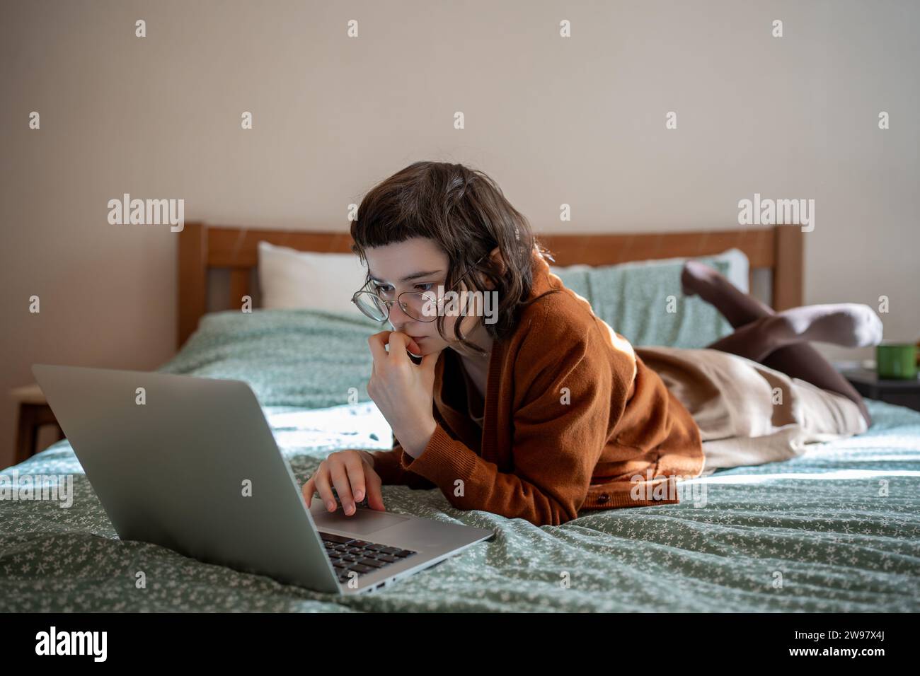 Concentrata adolescente che legge libri online, scorrendo i social network in Internet su un computer portatile Foto Stock