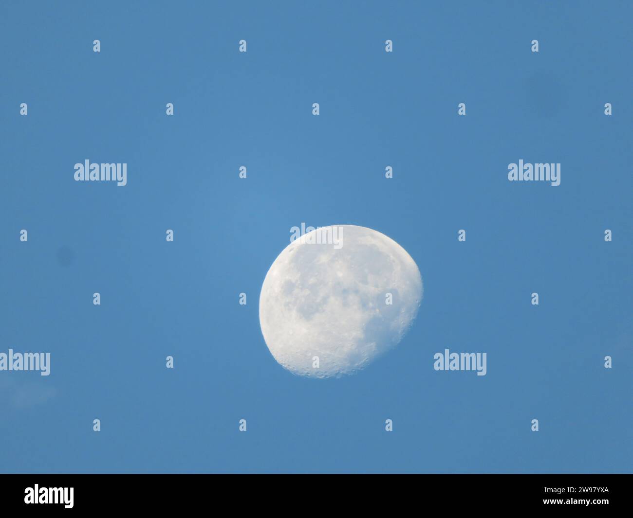 Un cielo celeste con una luna piena al centro, circondato da un cielo blu Foto Stock