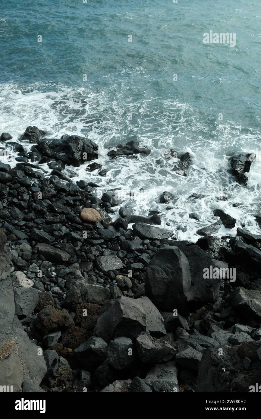 Un paesaggio roccioso su una costa, con onde che si infrangono sullo sfondo Foto Stock